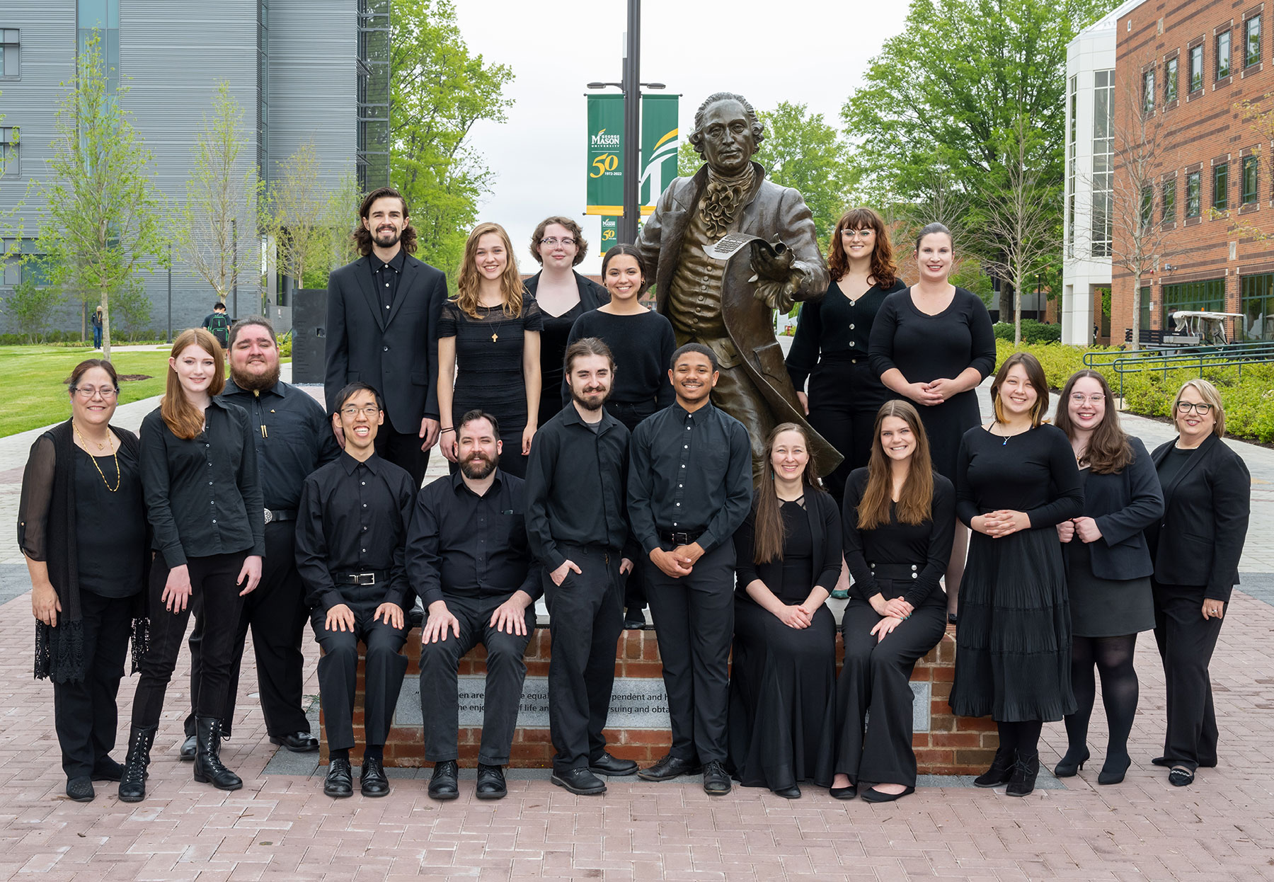 The University Singers posing by the statue of George Mason on the Fairfax campus.