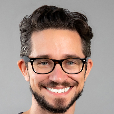 Dr. William Kenlon wearing glasses with brown hair and a beard with warm smile.