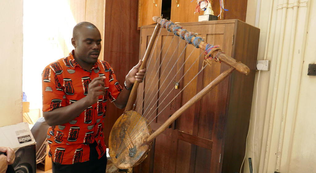 Leonard Wekesa demonstrates an East African instrument to Mason students on study abroad trip