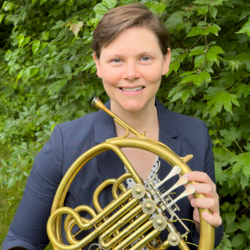 Dr. Caroline Steiger holding her horn with a blue blazer outside