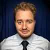 Brendan Sweeney wearing dress shirt with black tie against blue background