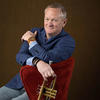 Professor Graham Breedlove holding his trumpet in a red velvet chair